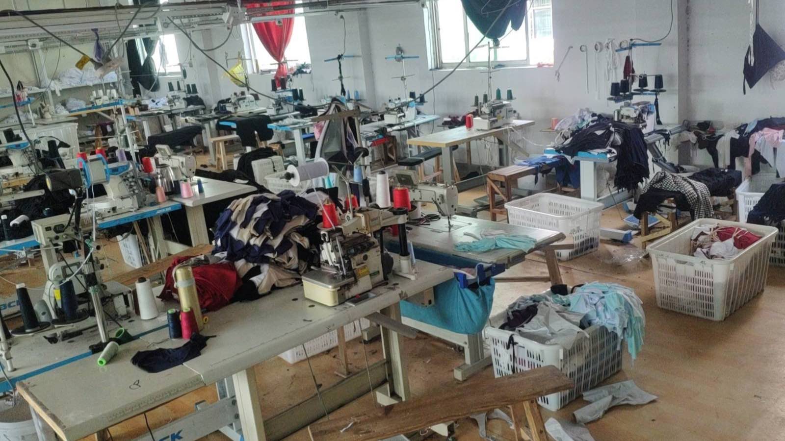 Close-up of overlock machines and thread stands with garments in progress on the sewing line